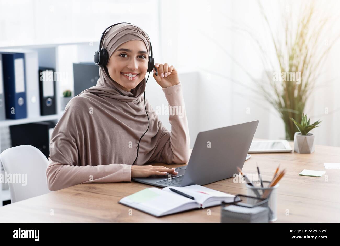 Arabischer weiblicher Mitarbeiter im Headset-Webinar auf einem Laptop im Büro Stockfoto