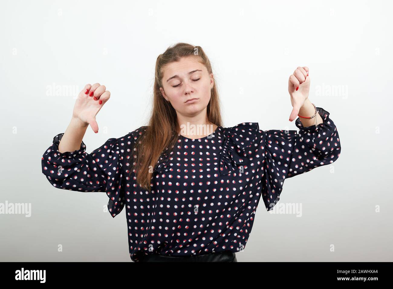 Mädchen in einem schwarzen Kleid mit weißen Kreisen umgekippt zeigt Daumen nach unten gedreht Stockfoto
