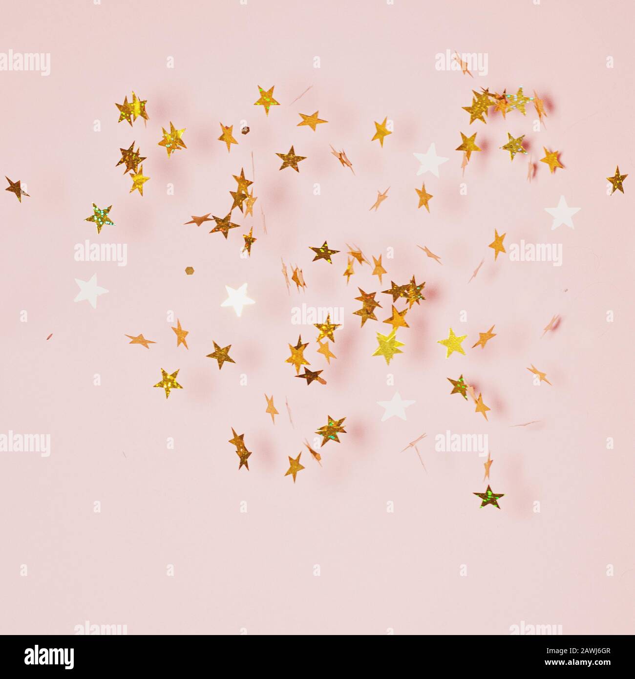 Goldenes Konfetti bläst auf rosafarbenem Hintergrund Stockfoto