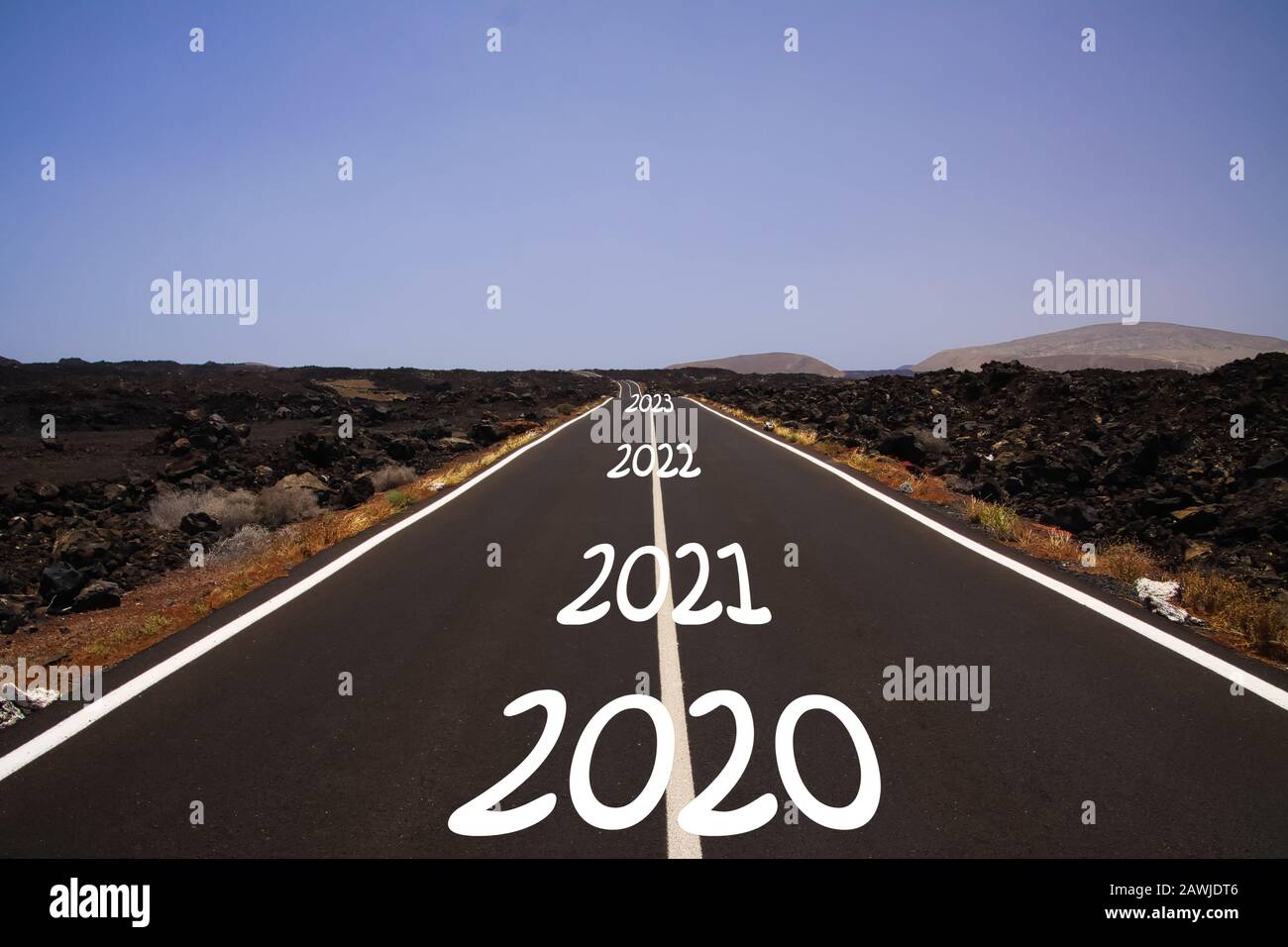 Langes hartes Erfolgskonzept: Blick auf endlose Asphaltstraße durch trockene, aride Vulkanlandschaft mit den Jahren 2020, 2021, 2022, 2023 Stockfoto