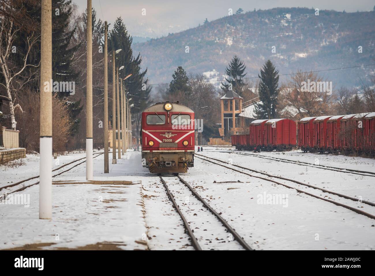 Velingrader Bahnhof, Bulgarien - 8. Februar 2020: Zug mit roter Lok und grünen Wagen kommt zum Bahnhof. Stockfoto