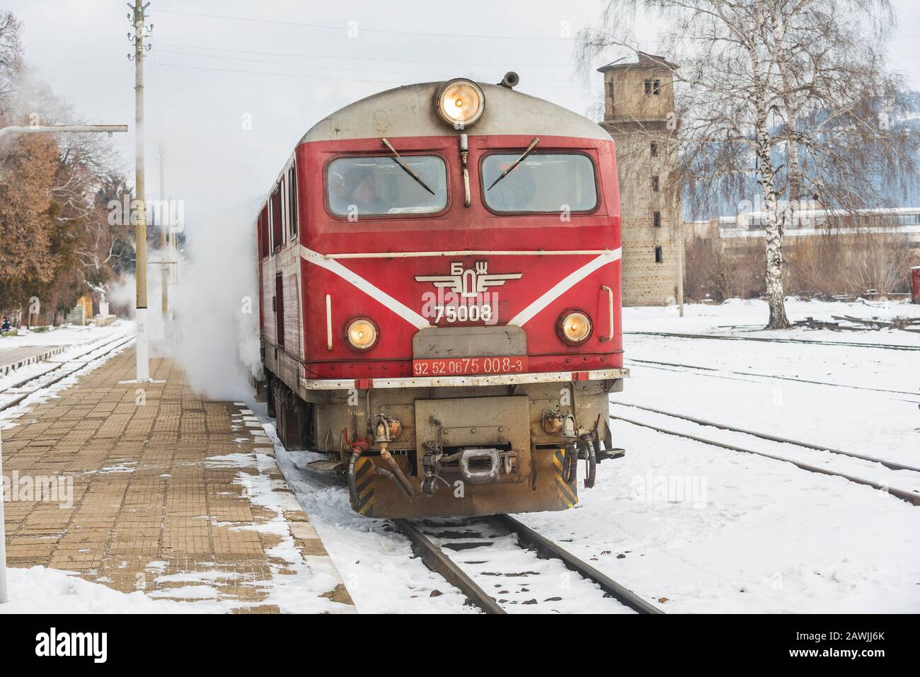 Velingrader Bahnhof, Bulgarien - 8. Februar 2020: Zug mit roter Lok und grünen Wagen kommt zum Bahnhof. Stockfoto