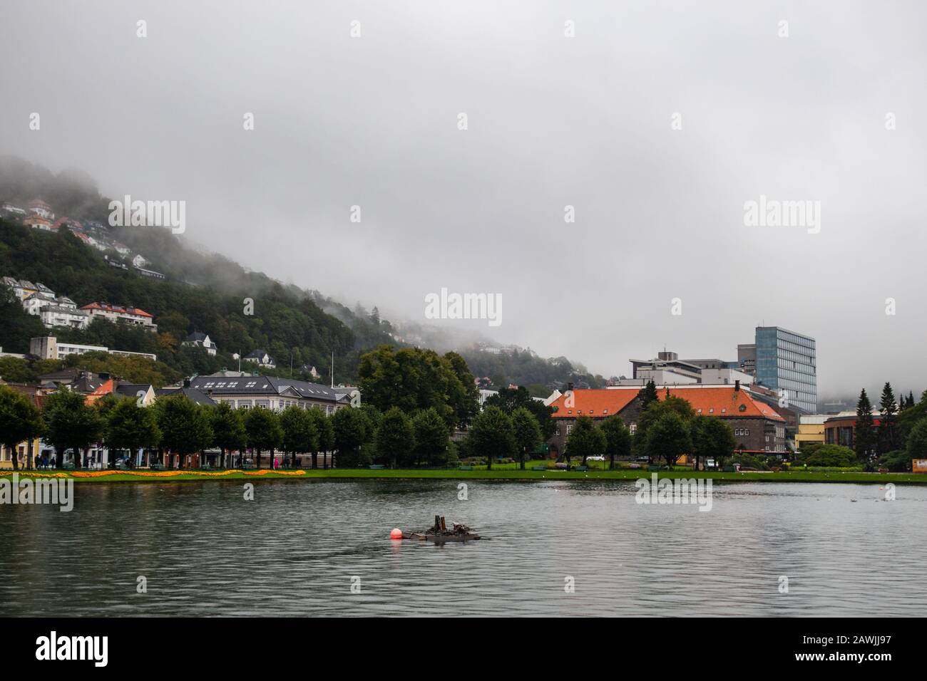 Editorial 09.04.2019 Bergen Norwegen Blick auf den zentralen Park mit See in der Stadt mit Nebel, der die Häuser am Hang des Berges Floyfjellet bedeckt Stockfoto