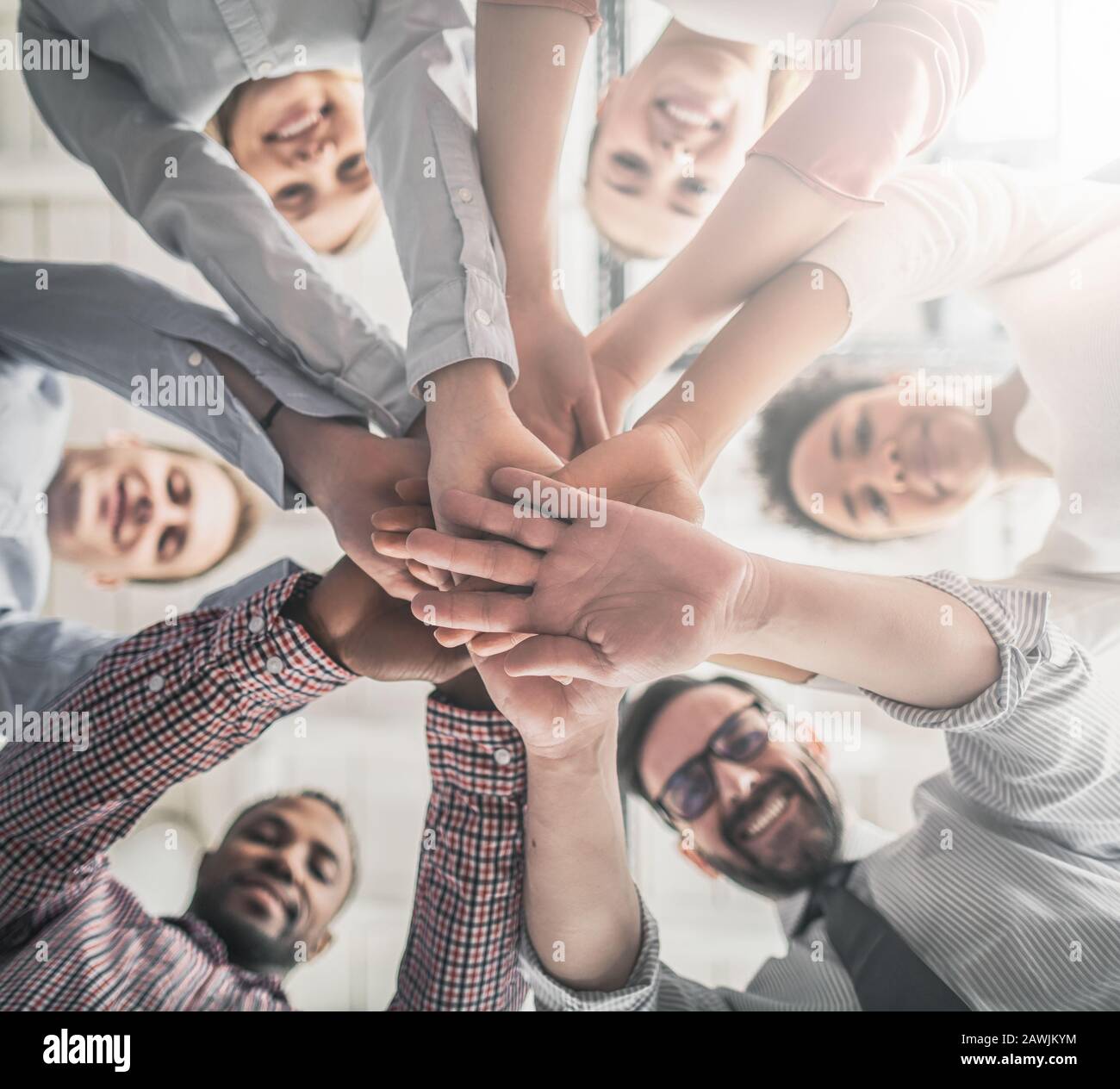 Nahaufnahme der jungen Geschäftsleute, die ihre Hände zusammenlegen. Handstapel. Einigkeit und Teamarbeit. Stockfoto