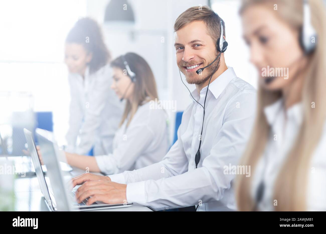 Call Center Arbeitnehmer, der von seinem Team begleitet. Lächelnd customer support Operator bei der Arbeit. Junge Mitarbeiter mit einem Headset. Stockfoto