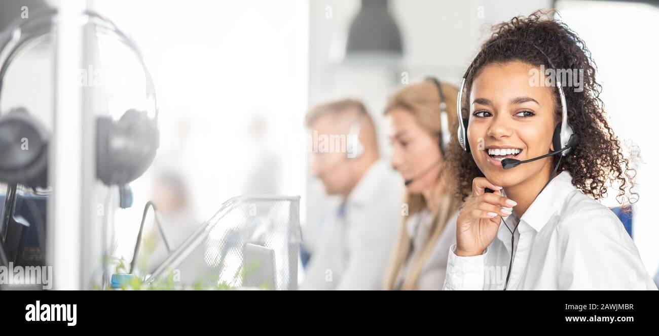 Call Center Mitarbeiter durch ihr Team begleitet. Lächelnd customer support Operator bei der Arbeit. Junge Mitarbeiter mit einem Headset. Stockfoto