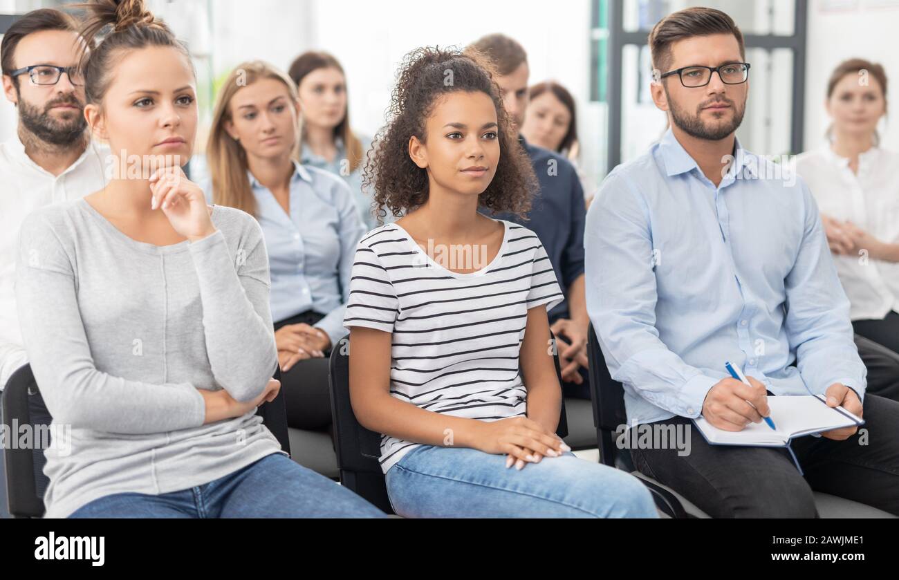 Geschäftskonferenzkonzept. Junge Leute sitzen zusammen auf Konferenz und Listenning. Multiethnische Gemeinschaft. Stockfoto