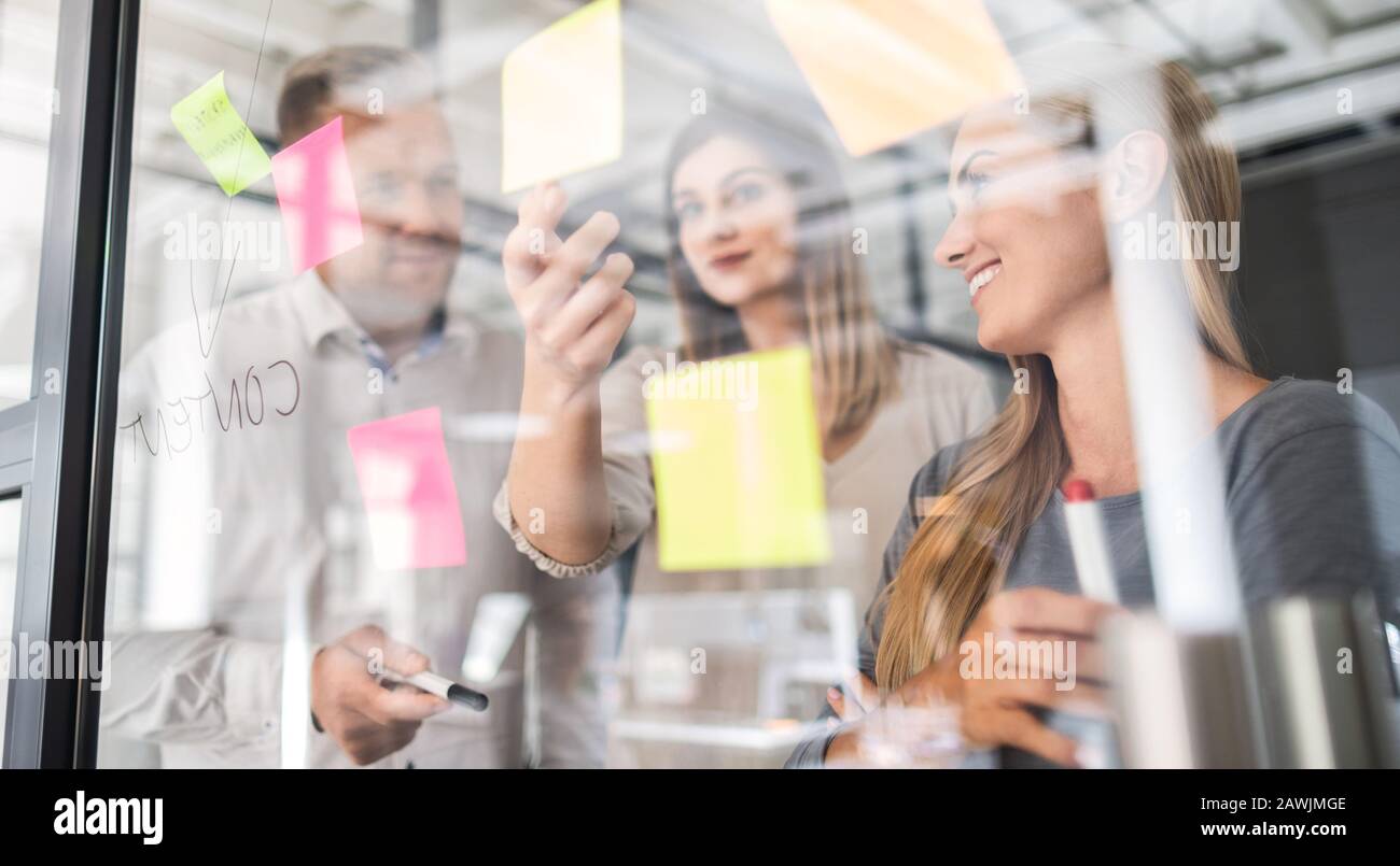 Business Leute, die im Büro und Post-it Notizen Idee zu teilen. Brainstorming Konzept. Haftnotiz auf einer Glaswand. Stockfoto