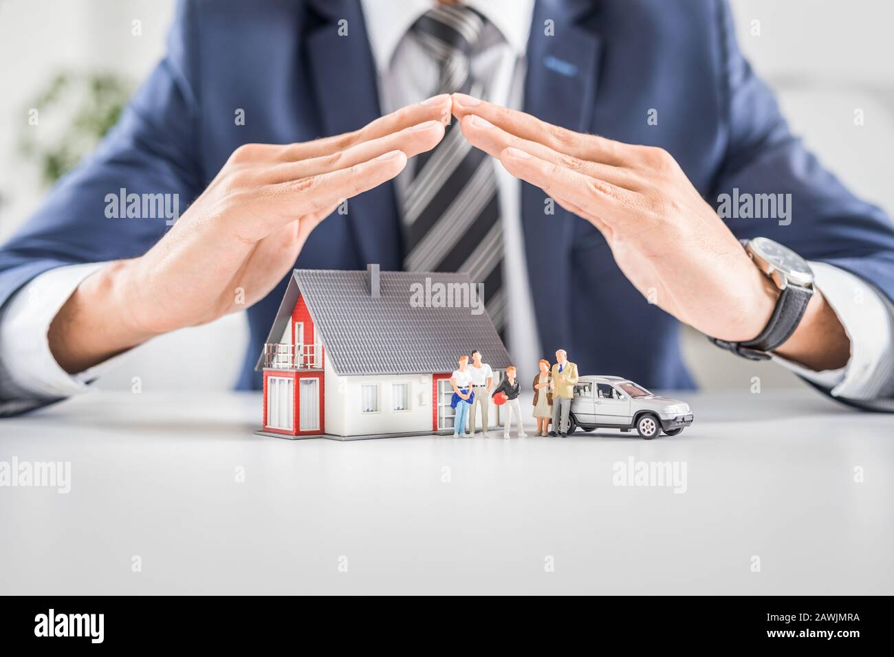 Versicherungshaus, Auto und Familie leben Konzept. Der Versicherungsvertreter stellt die Spielzeuge vor, die die Deckung symbolisieren. Stockfoto