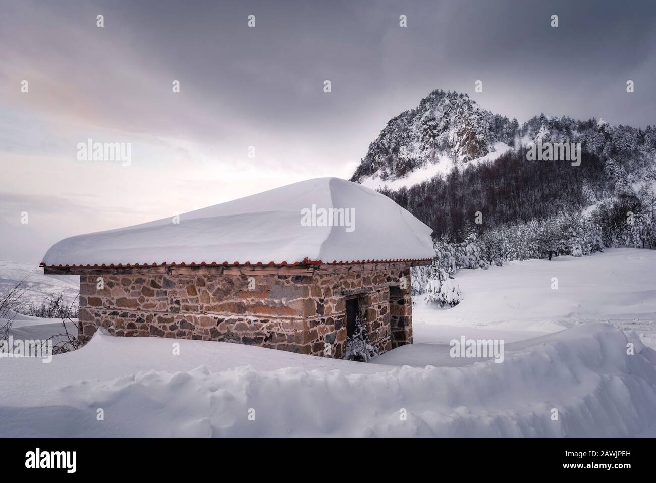 Weißer Schnee bedeckt ein Steinhaus unter wintertrübem Himmel Stockfoto