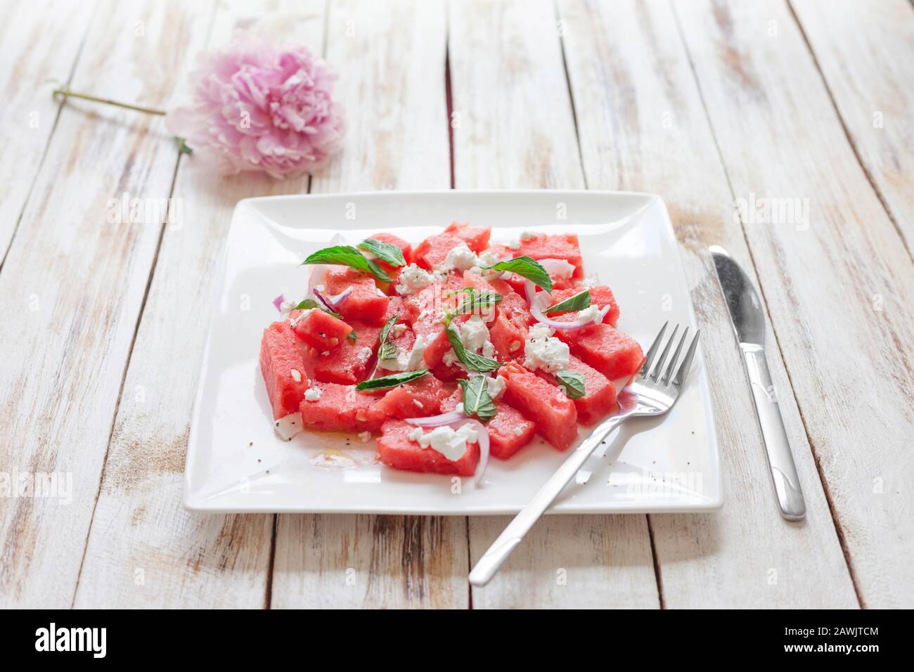 Frischer Wassermelonsalat mit Fetakäse und Minze auf weißem Teller Stockfoto