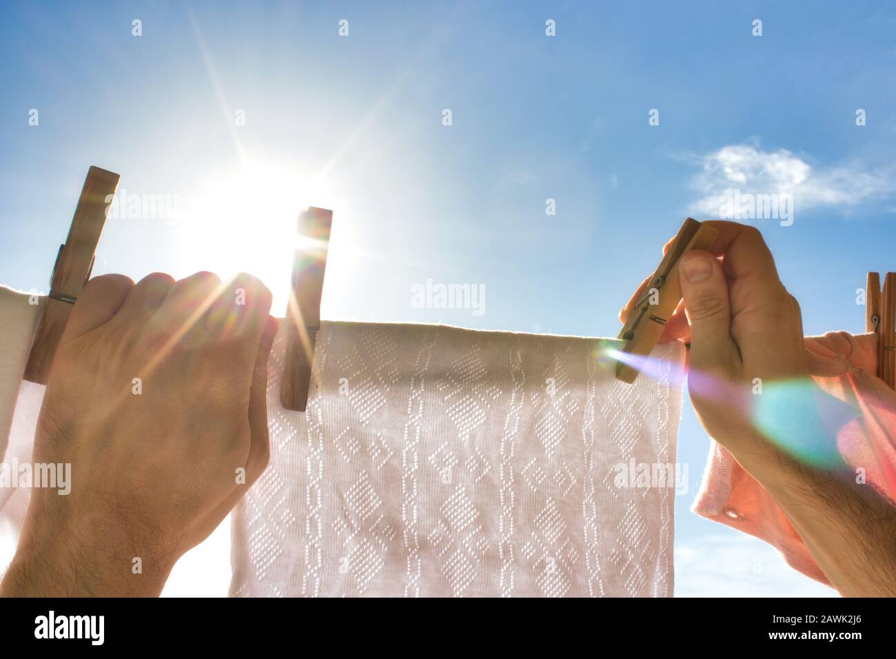 Ein Paar Hände, die nach oben greifen, um ein weißes Hemd an einer Waschstraße zu hängen Stockfoto