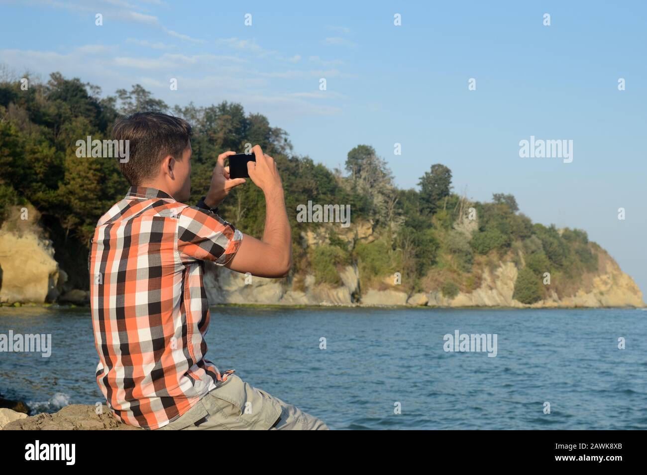 Ein junger Mann, ein Reisender mit Handy, nutzt moderne Technologien der Breitband-Mobilfunknetzabdeckung für die Kommunikation vor dem Hintergrund von Stockfoto