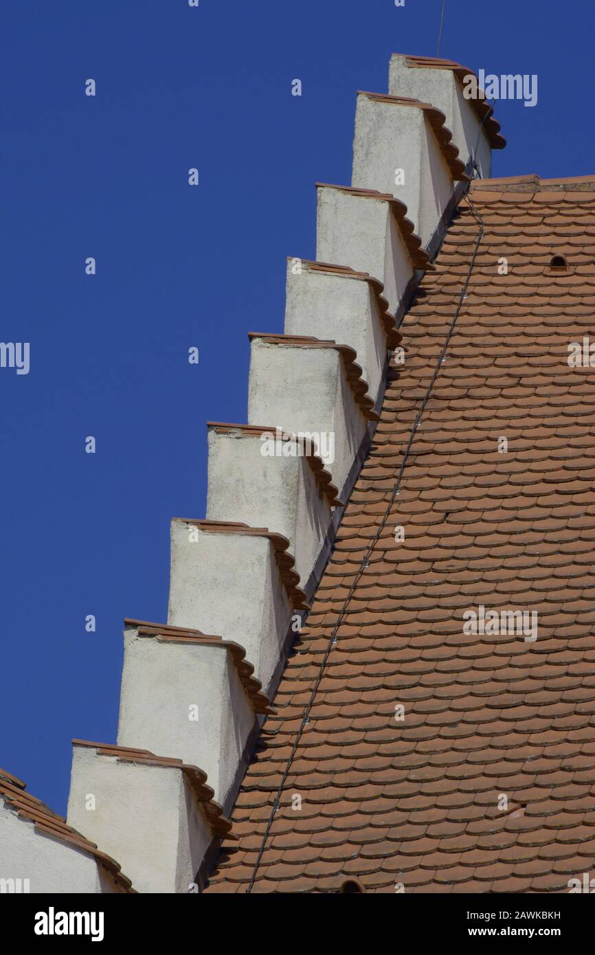 Detail eines historischen Hausdachs vor blauem Sommerhimmel, Dach oben auf den roten Ziegeldächern des historischen Hauses Stockfoto
