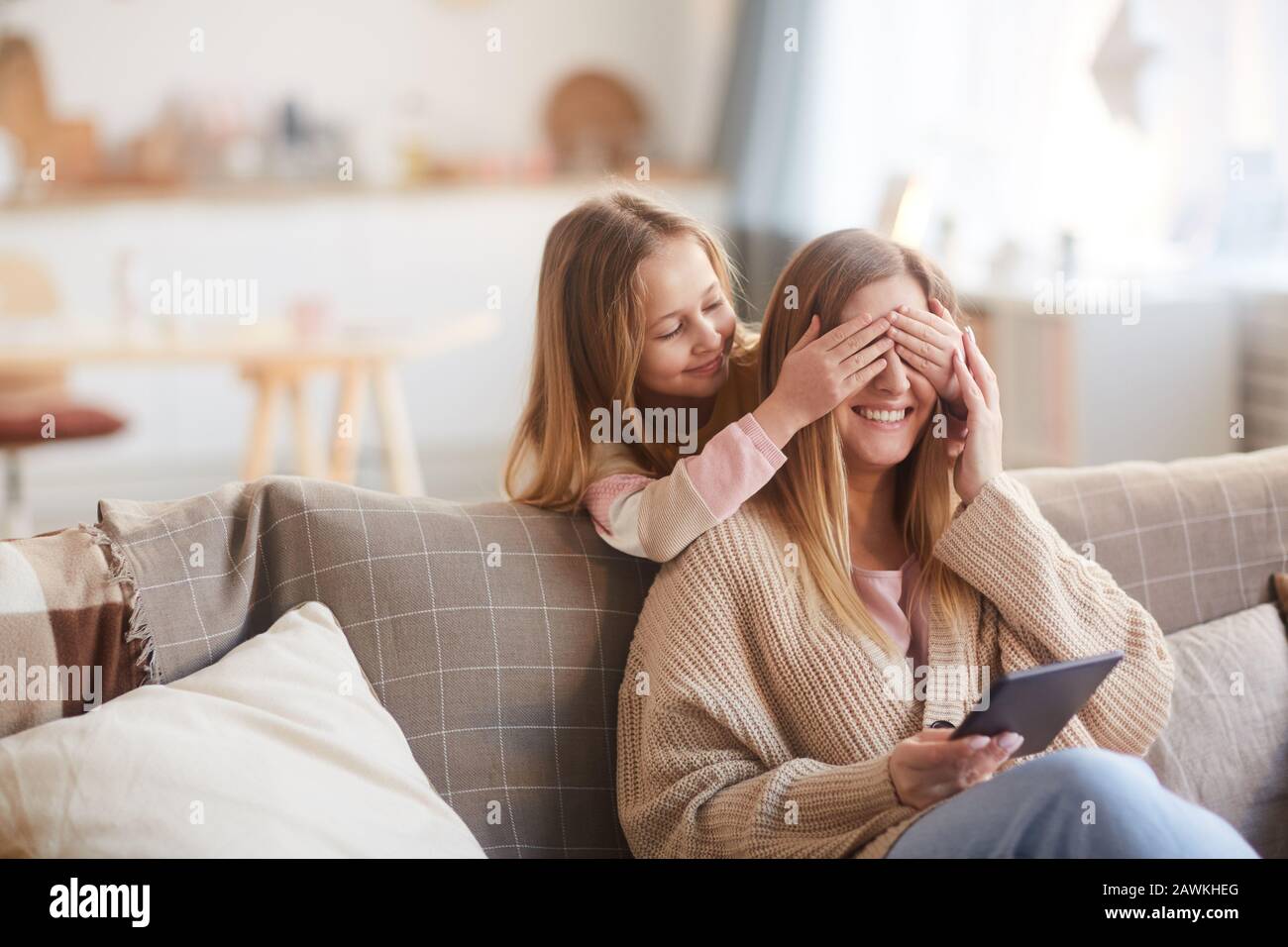 Warmer gezungter Portrait von niedlichem Mädchen, das einen Buh mit fröhlicher junger Mutter spielt, während er sie am Muttertag überraschte, kopiere Raum Stockfoto