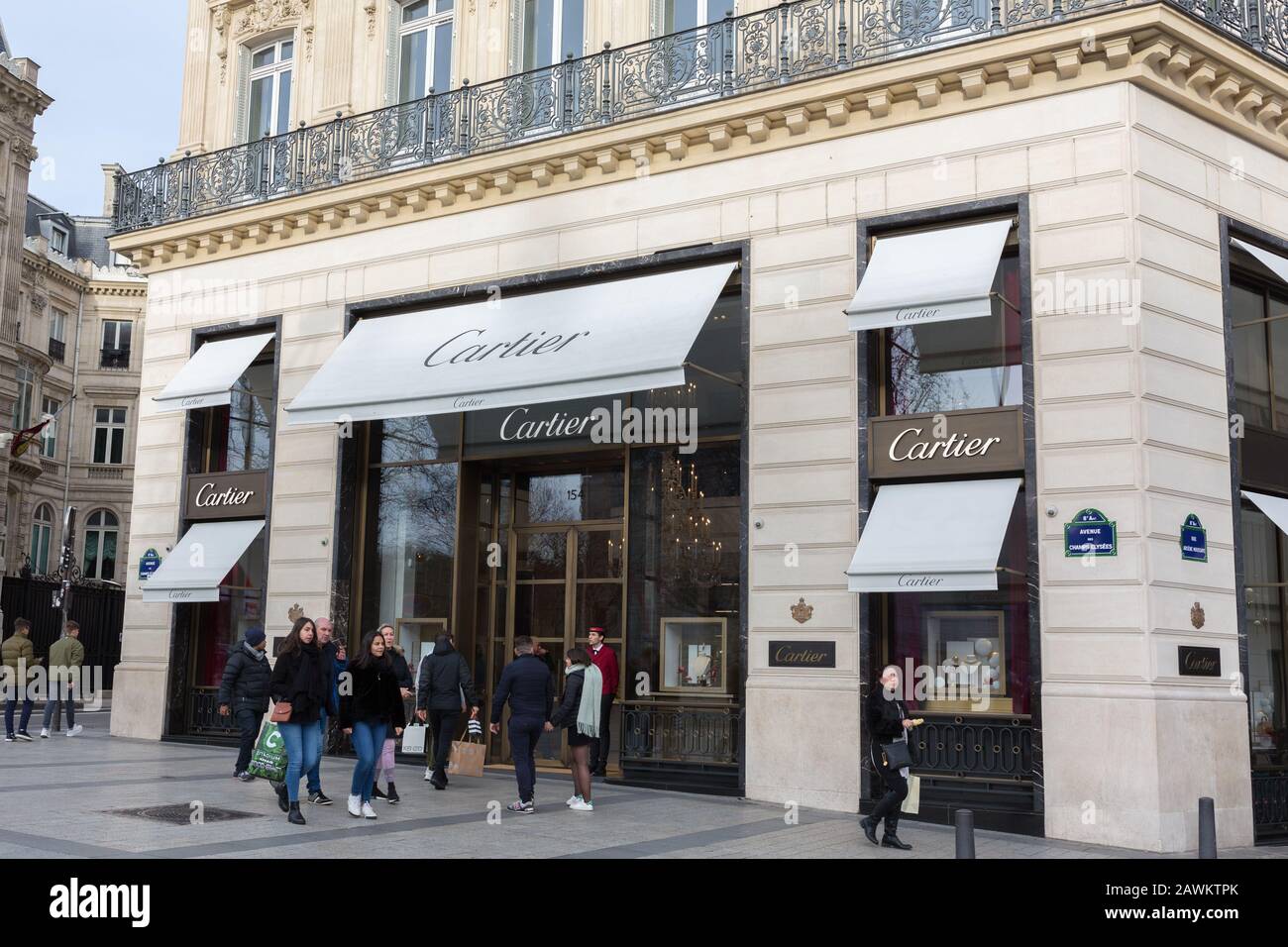 Seitenansicht auf dem Cartier-Laden an den Champs-Elysées. Menschen (Käufer?) mit Taschen laufen vorbei. Die Marke "Cartier" gehört zur Richemont Group. Stockfoto