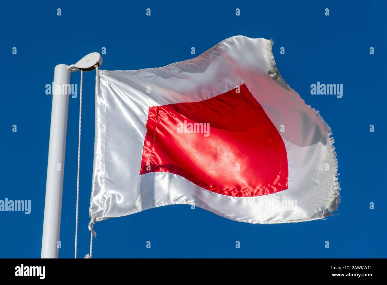 RAS al Khaimah Flagge (rot und weiß) in den Vereinigten Arabischen Emiraten (VAE) nördlich von Dubai, weht im Wind auf einem blauen Himmelshintergrund. Stockfoto