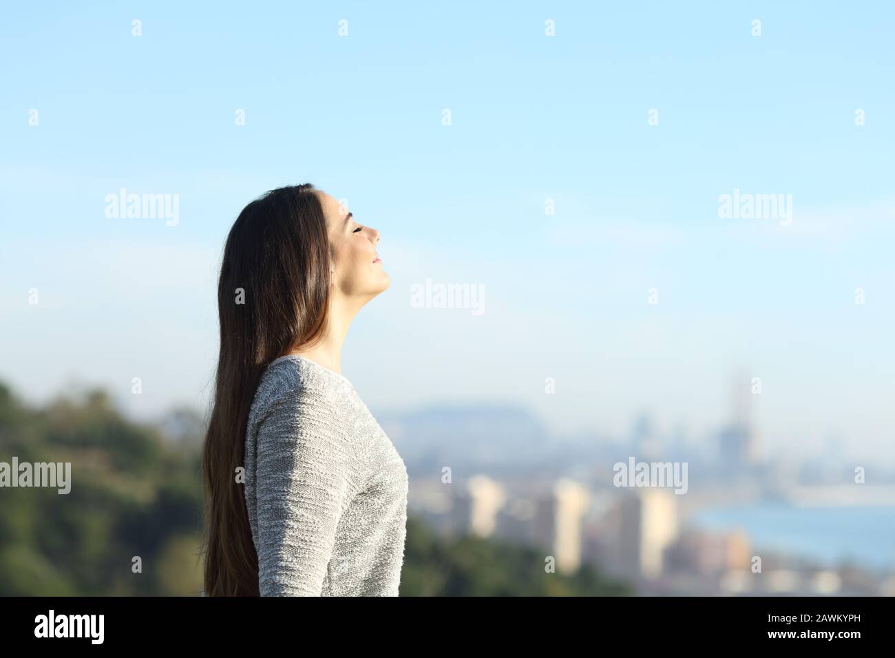 Seitenansicht Porträt eines Mädchens, das frische Luft mit einer Stadt im Hintergrund atmet Stockfoto