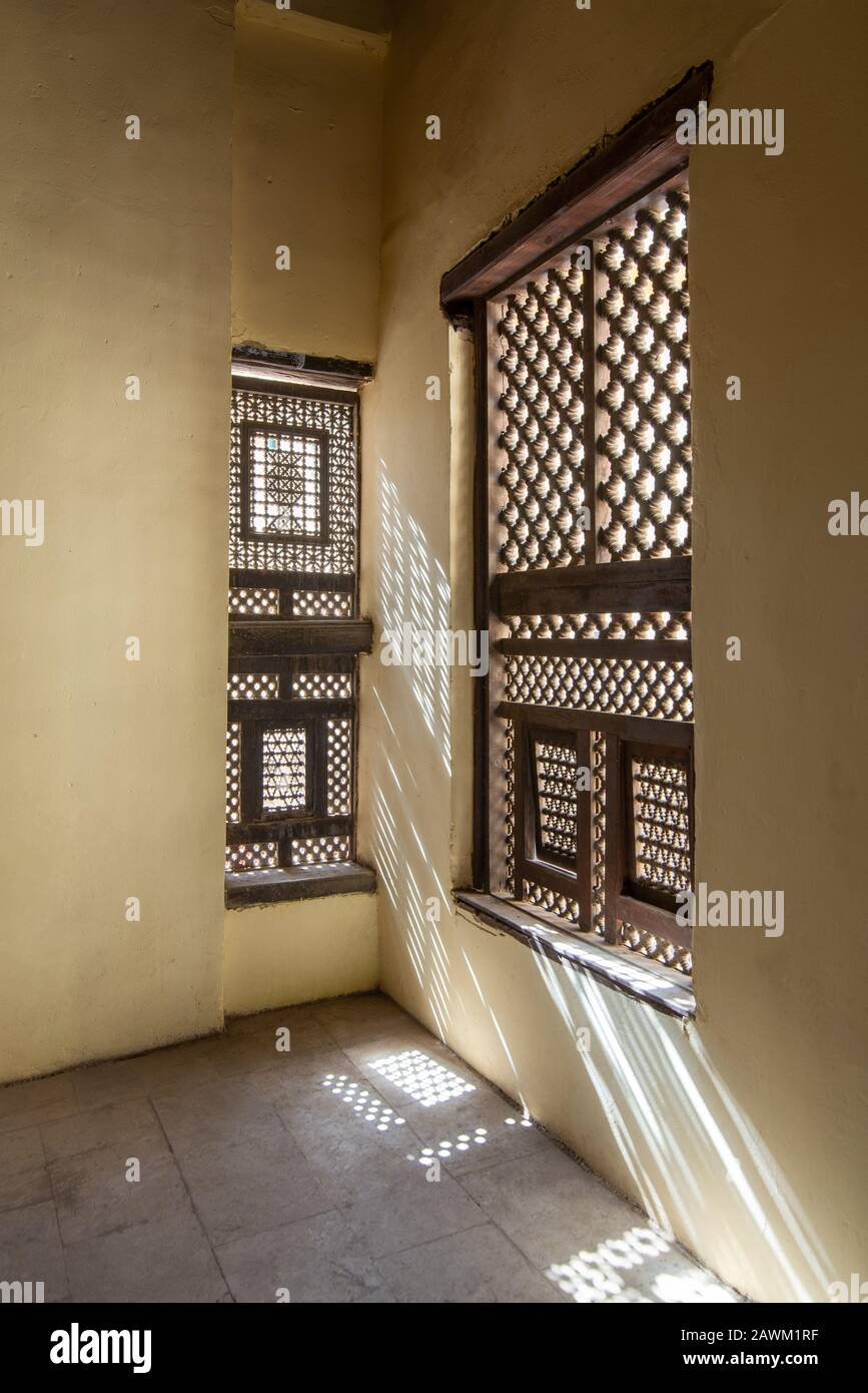Ecke zweier verzierter Fenster aus Interleaved Grunge aus Holz - Mashrabiya - in Steinmauer am verlassenen Gebäude Stockfoto