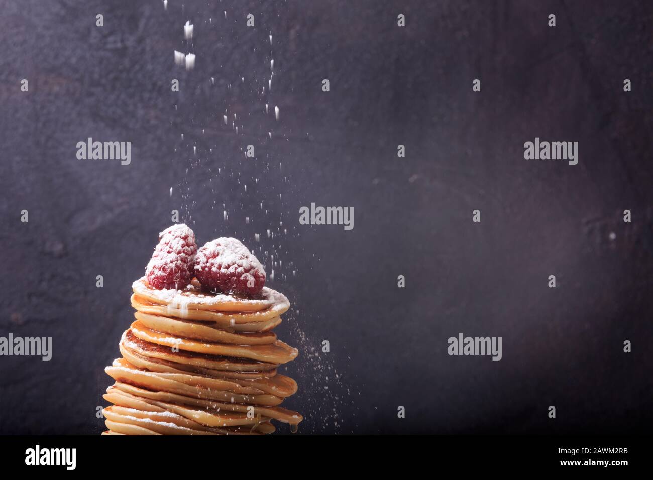 Pfannkuchen mit Himbeeren oben. Hausgemachtes Dessert. Maslenitsa-Konzept. Dunkelgrauer Hintergrund. Absieden von Puderzucker. Horizontal Stockfoto