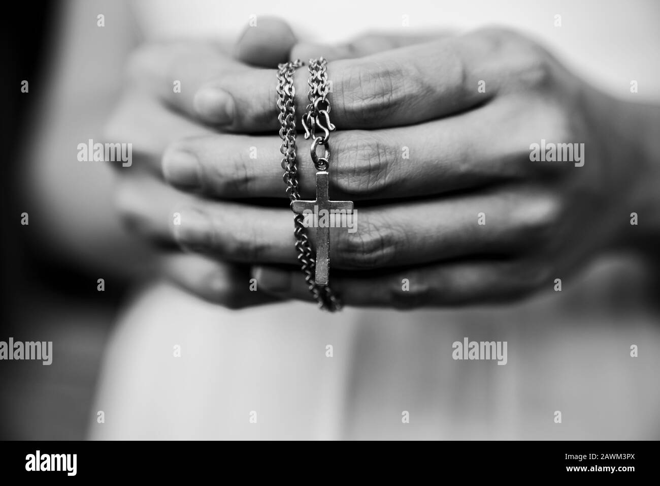Schwarz-weiß der Frau betet mit einem Perlen Rosary mit Jesus Christus im Kreuz oder Kruzifix auf schwarzem Hintergrund. Stockfoto