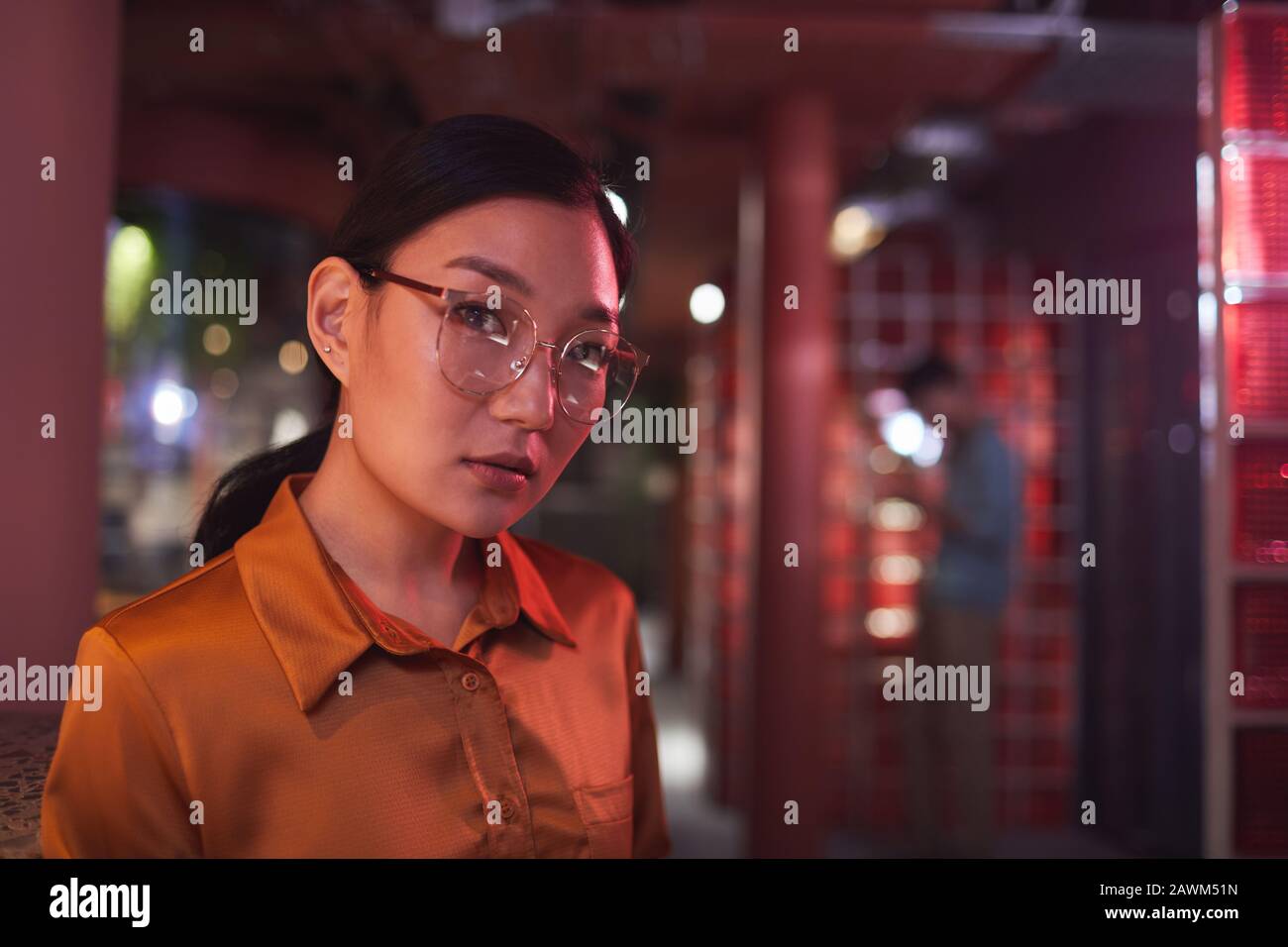 Kopf- und Schulterporträt zeitgenössischer asiatischer Geschäftsfrau, die die Kamera betrachtet, während sie in futuristischem Büroinneren arbeitet, Platz für Kopien Stockfoto