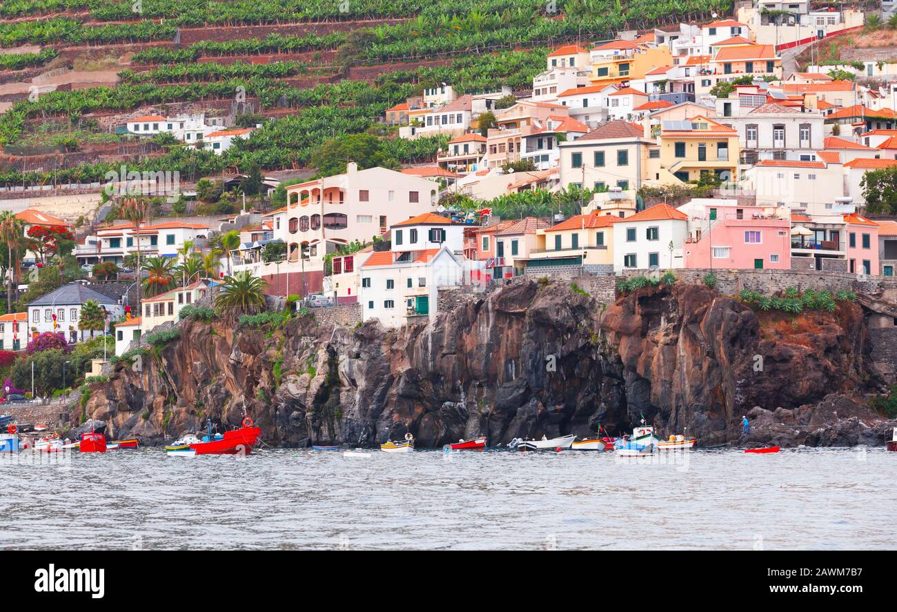 Fischerboote ankerten in der Nähe der felsigen Küste. Küstenlandschaft von Funchal, der Hauptstadt der Insel Madeira, Portugal Stockfoto