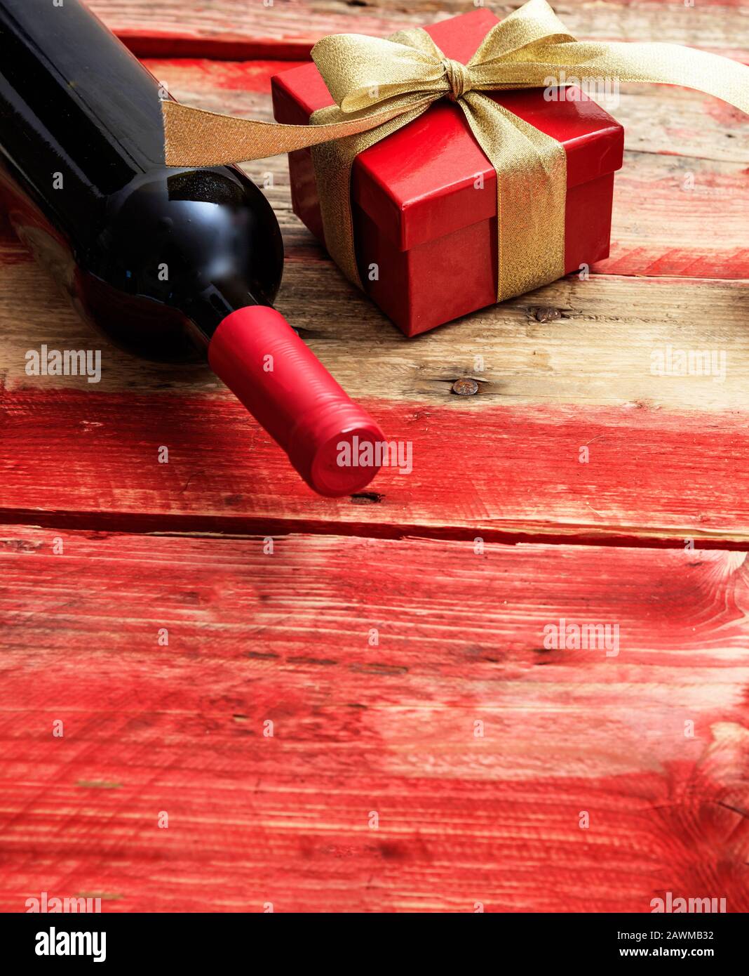 Valentines Tageskonzept. Rotweinflasche und ein Geschenk auf Holz, Kopierraum Stockfoto