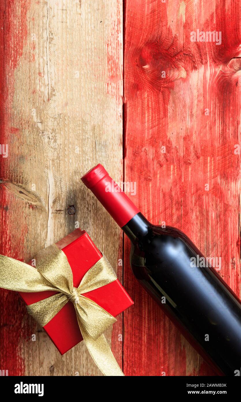 Valentines Tageskonzept. Rotweinflasche und ein Geschenk auf Holz, Draufsicht Stockfoto