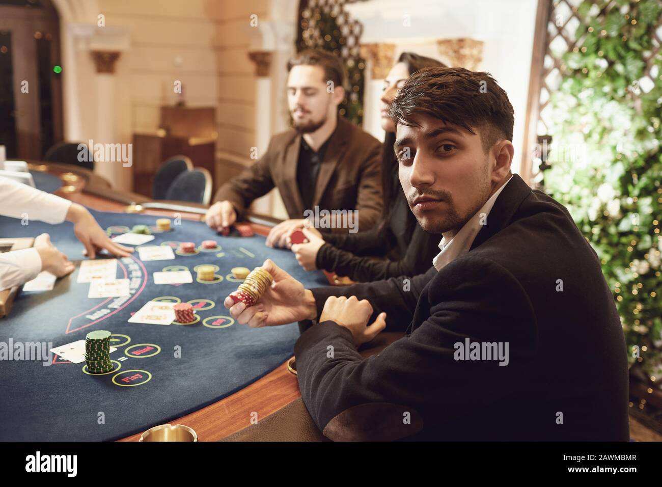 Ein Kerl mit Chips in seinen Händen spielt Poker mit Freunden in einem Casino. Stockfoto