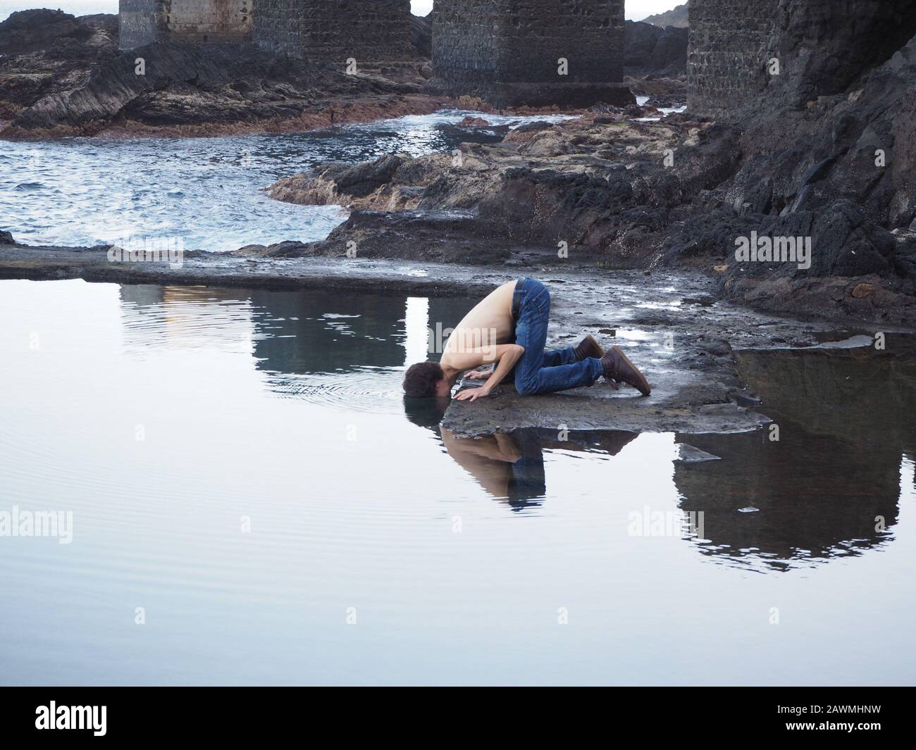 Der Mann mit dem Kopf auf dem Wasser sieht sich wie Narzissus-Mythos aus Stockfoto