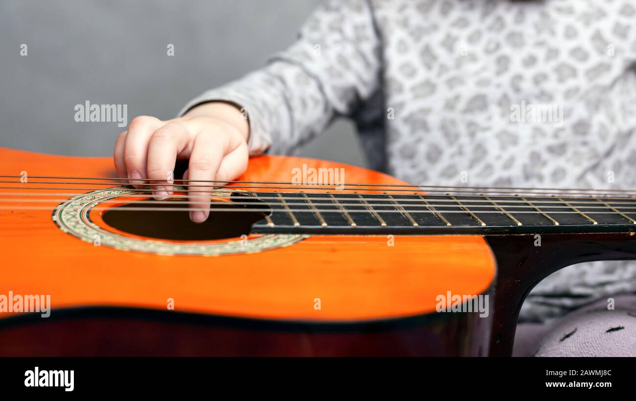 Kleines Mädchen und akustische Gitarre. Kind lernt Gitarre spielen. Stockfoto