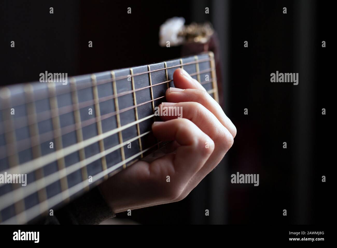 Weibliche Hand spannt einen Akkord an einer akustischen Gitarre. Stockfoto