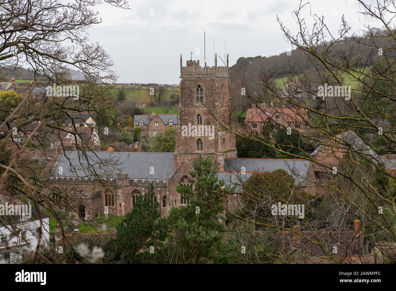 Weiter erhöhter Blick auf die St Mary's Church in Dunster Somerset. Teilweise verdeckt von Bäumen im Vordergrund. Stockfoto