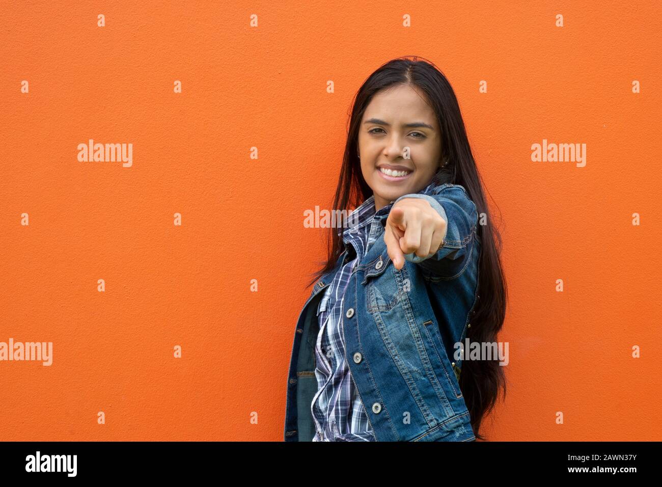 Porträt Einer Lächelnden Jungen Frau, Während Sie Gegen Orange Wall, Panama, Mittelamerika, Steht Stockfoto
