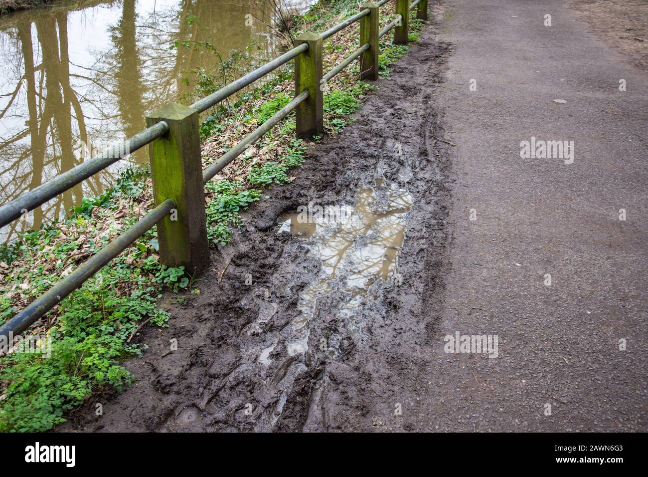 Eine schlammige Pfütze mit Fußabdrücken und Radspuren neben einem Fußweg neben dem Fluss Frome In Frome Somerset Stockfoto