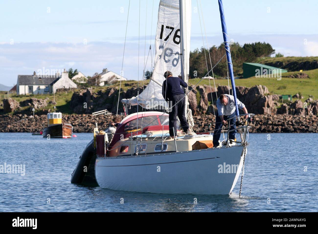 Crew, die das Hauptsegel hochzog und den Anker auf der Segelyacht, Port Mor, Isle of Muck, Inner Hebrides, Schottland, schleppte Stockfoto