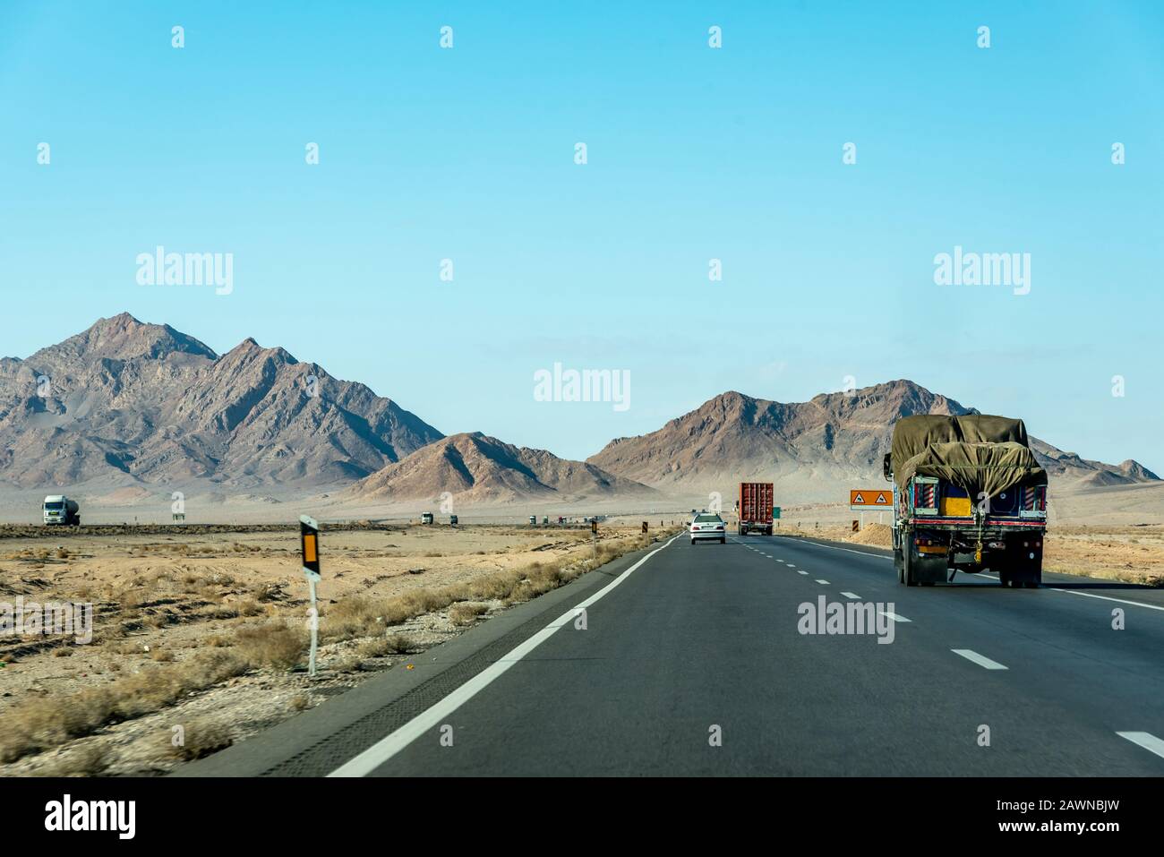 Blick auf die Straße mit privaten Autos und Lastwagen zwischen Kerman und Yazd, Iran Stockfoto