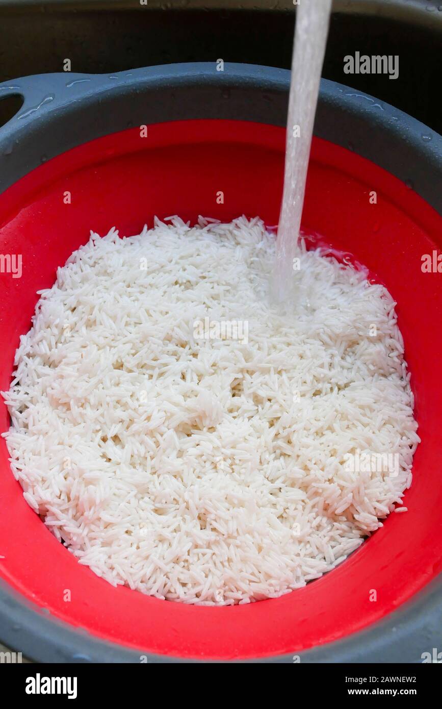 Bereiten Sie Reis zum Kochen vor, indem Sie ihn durch Wasser in einem Sieb  waschen Stockfotografie - Alamy