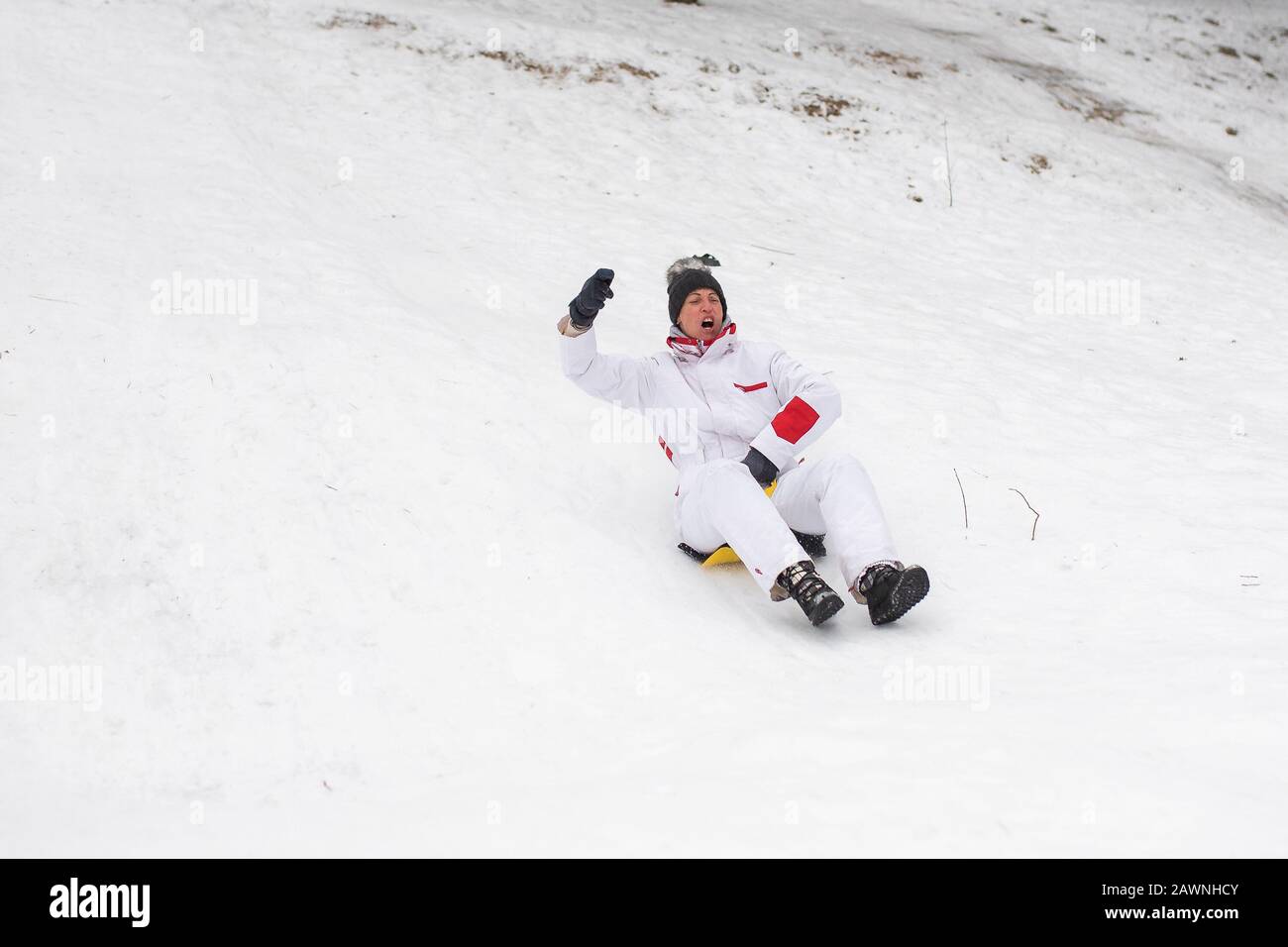 Eine Erwachsene Frau reitet auf Eisschlitten vom Berg. Emotional.Winterspaß. Stockfoto