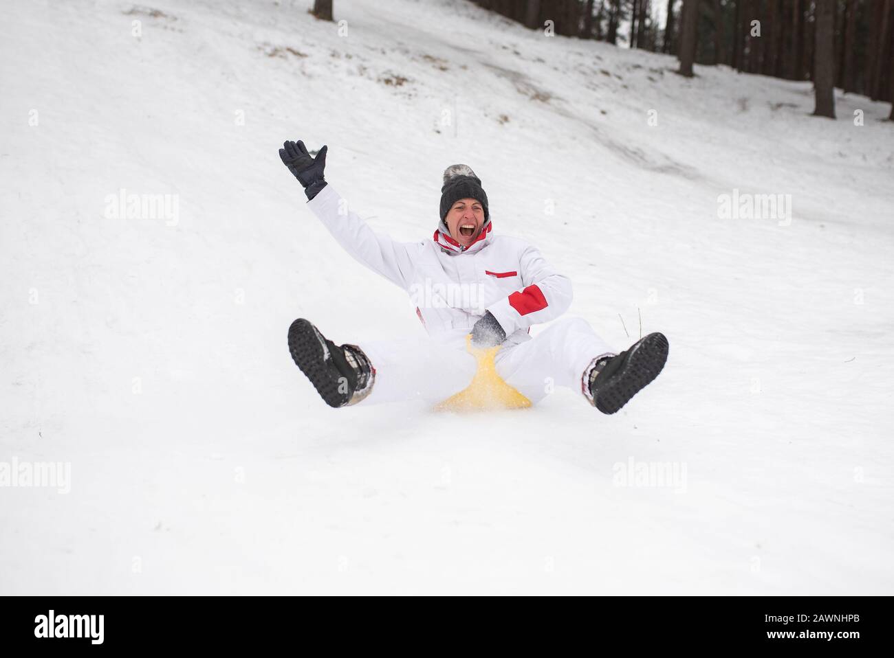 Eine Erwachsene Frau reitet auf Eisschlitten vom Berg. Emotional.Winterspaß. Stockfoto