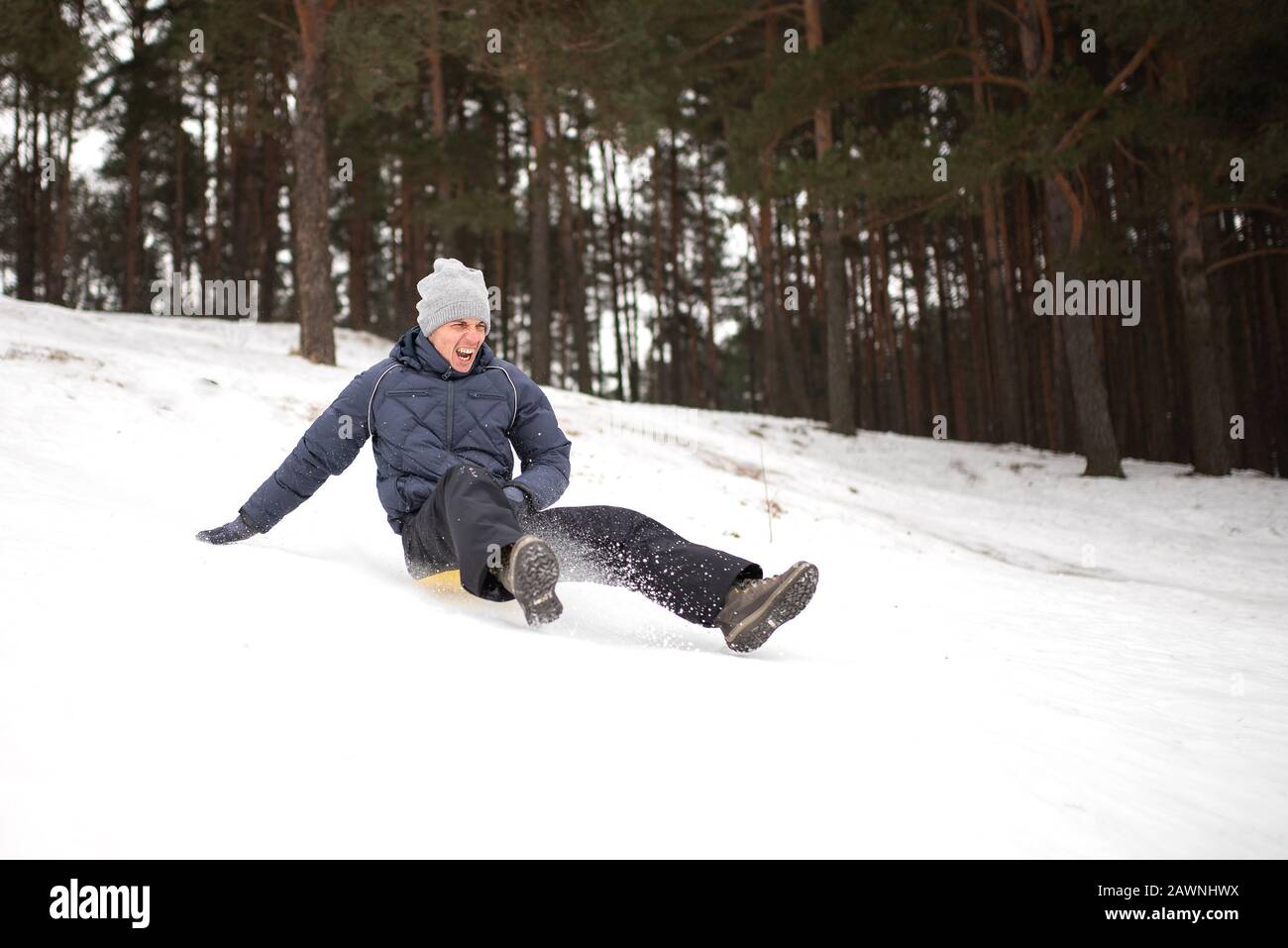 Erwachsener reitet von einem steilen Berg aus auf Schlitteneis. Winterspaß. Stockfoto