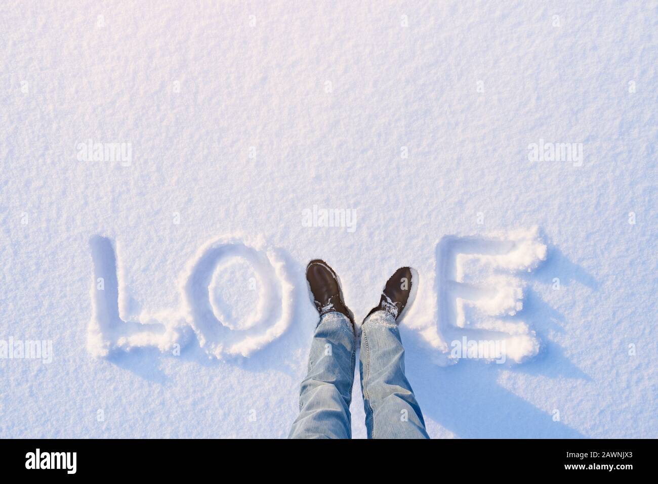 Ursprünglicher Hintergrund für eine Karte zum Valentinstag. Das Wort "Liebe", das im Schnee steht Stockfoto