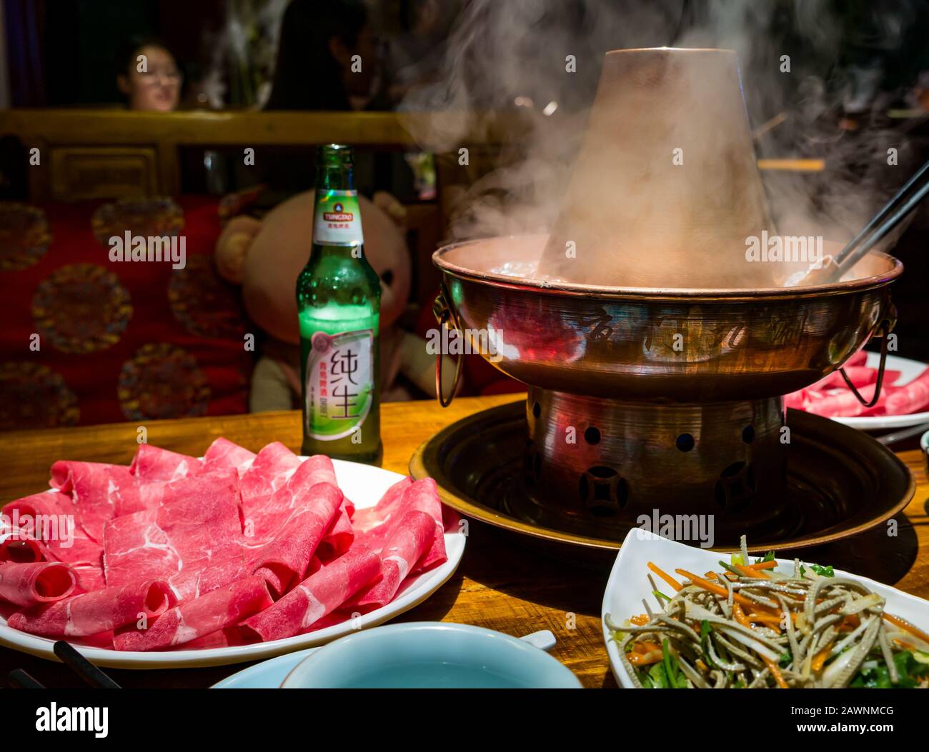 Mongolischer Hotspot mit Fleischscheiben, serviert am Restauranttisch mit lokalem Tsingtao-Bier, Xi Cheng Hutong District, Peking, China, Asien Stockfoto