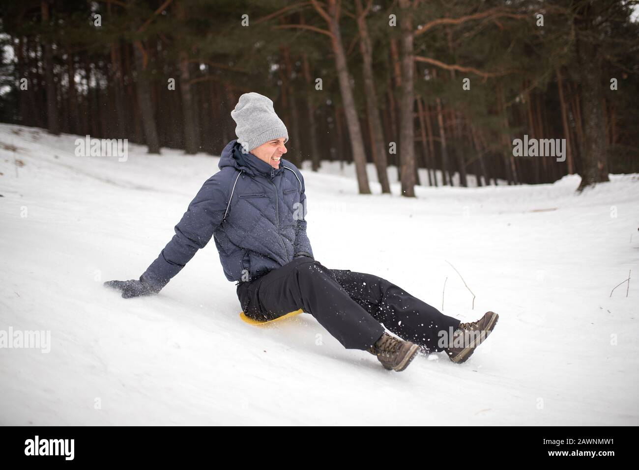 Erwachsener reitet von einem steilen Berg aus auf Schlitteneis. Winterspaß. Stockfoto
