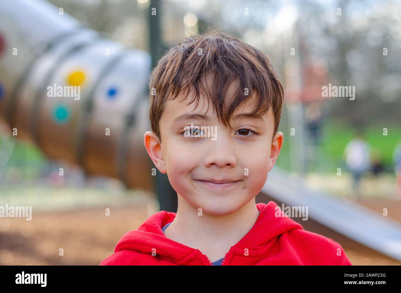 Porträt eines jungen, fröhlichen, lächelnden Jungen auf einem Spielplatz. Stockfoto