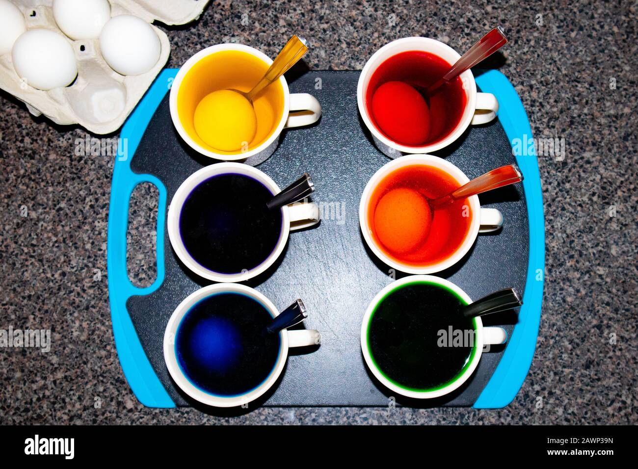 Ostereier, die mit Farbstoff, Kaffeetassen und Löffeln aus der Obersicht gefärbt werden Stockfoto