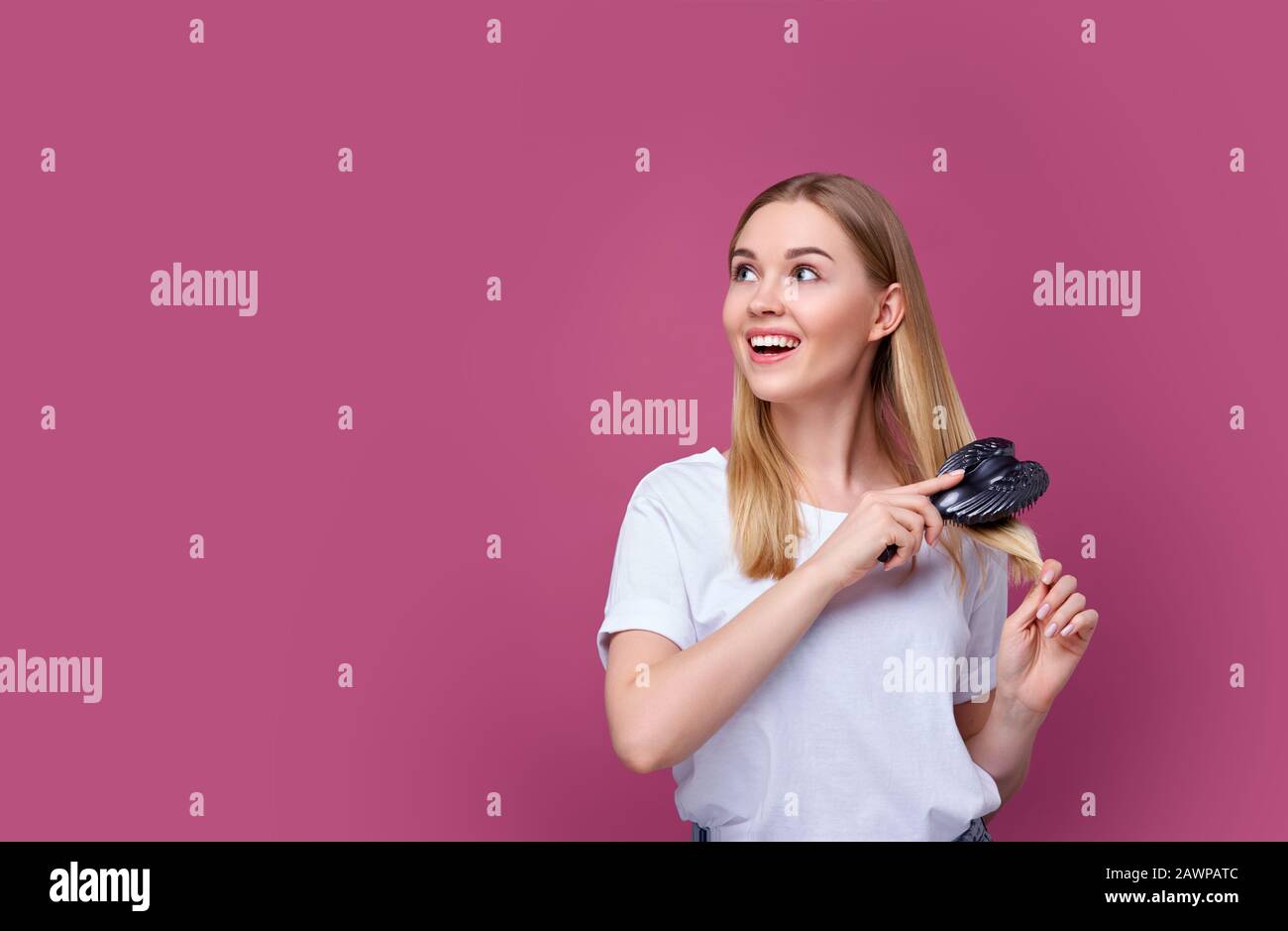 Schöne lächelnde Frau, die ihr Haar mit einem Kammaufsatz putzt Stockfoto