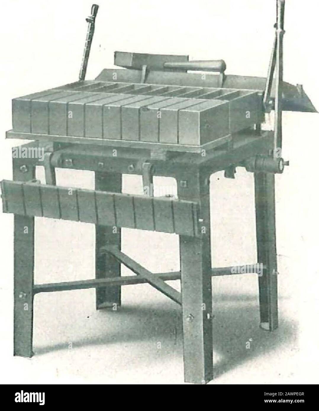 Betonmaschinen: Triumph, Wizard und Knox Block Machines . in der Abbildung. Die angelieferten Backsteine sind mit der Vorderseite nach oben auf der Palette und die Palette kann bequem aus der Maschine entfernt werden, ohne dass ein spezieller Träger verwendet wird. Bei der Herstellung von Zierfackeln werden die Zierfackeplatten lose aus dem Backstein entnommen, sobald sie auf der Palette umgedreht werden. Ein Satz oft Stirnplatten ist alles, was erforderlich ist, um eine Maschine voller Zierflächen bei jeder Operation zu machen. Um Brick so Zu Machen, dass die Plane nach oben Entfernt wird und die Palette auf dem Maschinenbett platziert wird. T Stockfoto