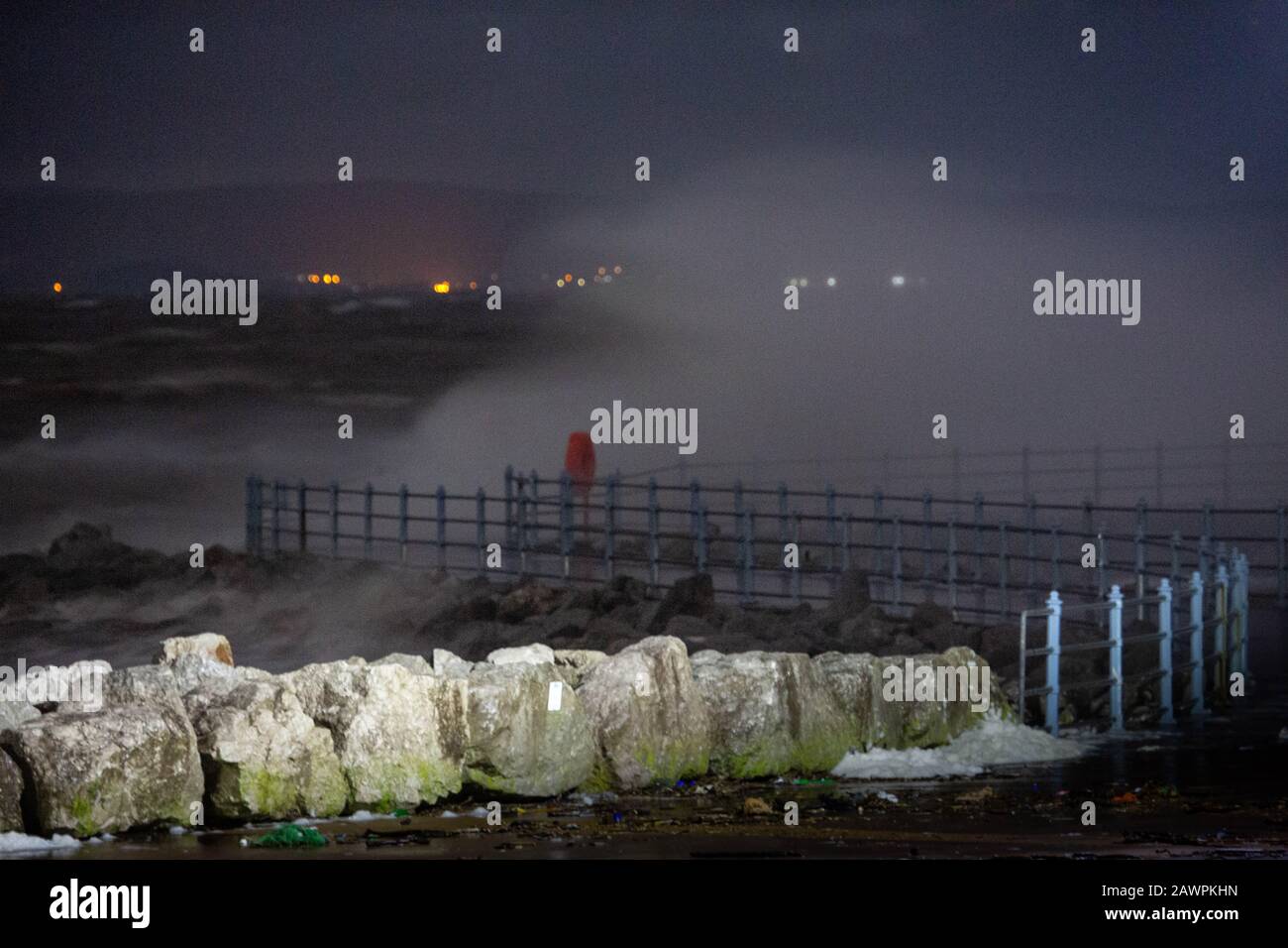 Grosvenor Break Water, Heysham, Lancashire, Großbritannien. Februar 2020. Heysham Hightidde heute Abend hat mehr Wellen über die Spitze des Breakwater mit He Lights of Ulverston im Hintergrund Credit gebracht: Photographing North/Alamy Live News Stockfoto